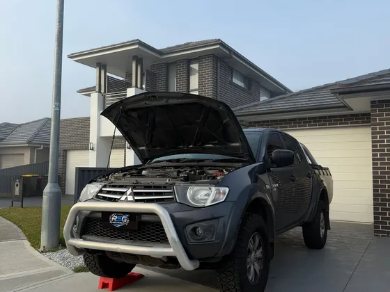 Mitsubishi ute on ramps being repaired in a customer driveway